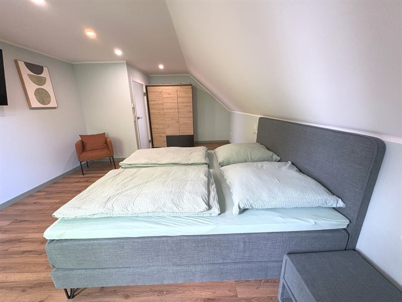 Helles Schlafzimmer 1 im Obergeschoss mit Doppelbett und Balkonzugang
